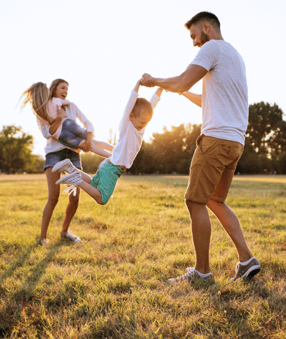 Un père et une mère joeunt dans un parc avec leurs enfants